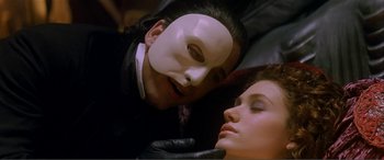 Movie still from “The Phantom of the Opera” (2004), directed by Joel Schumacher – A man and a woman wearing masks and gloves; Close Up shot, Over the shoulder angle