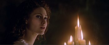 Movie still from “The Phantom of the Opera” (2004), directed by Joel Schumacher – A beautiful young lady looking at the camera with candles in the background; Close Up shot, Over the shoulder angle