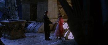 Movie still from “The Phantom of the Opera” (2004), directed by Joel Schumacher – A man and a woman holding hands while standing on a sidewalk; Wide shot, High angle