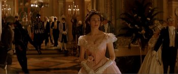 Movie still from “The Phantom of the Opera” (2004), directed by Joel Schumacher – A woman in a pink dress holding a white rose; Medium shot, Over the shoulder angle