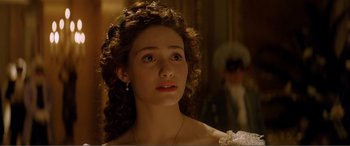 Movie still from “The Phantom of the Opera” (2004), directed by Joel Schumacher – A young woman in a white dress looking to her left; Close Up shot, Over the shoulder angle