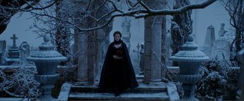 Movie still from “The Phantom of the Opera” (2004), directed by Joel Schumacher – A woman dressed in black holding a red rose in front of a stone arch; Wide shot, Low angle