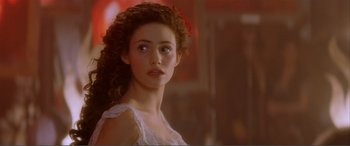 Movie still from “The Phantom of the Opera” (2004), directed by Joel Schumacher – A young woman with long curly brown hair wearing a white dress; Close Up shot, Over the shoulder angle