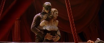 Movie still from “The Phantom of the Opera” (2004), directed by Joel Schumacher – A man and a woman dressed in costumes; Medium shot, Low angle