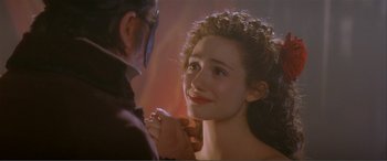 Movie still from “The Phantom of the Opera” (2004), directed by Joel Schumacher – A woman is smiling at the camera while a man holds her hand; Close Up shot, Over the shoulder angle