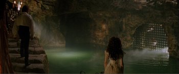 Movie still from “The Phantom of the Opera” (2004), directed by Joel Schumacher – A woman standing in front of a green cave; Extreme Wide shot, High angle
