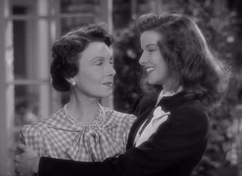 Movie still from “The Philadelphia Story” (1940), directed by George Cukor – A woman and a girl are smiling for the camera; Close Up shot, Over the shoulder angle