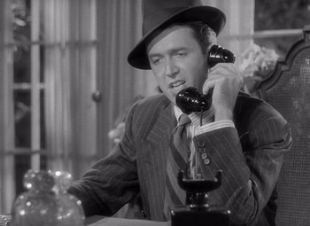 Movie still from “The Philadelphia Story” (1940), directed by George Cukor – A man wearing a suit and hat talking on a phone; Close Up shot, Low angle