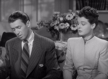 Movie still from “The Philadelphia Story” (1940), directed by George Cukor – A man and a woman sitting next to each other in front of flowers; Medium shot, High angle