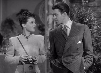 Movie still from “The Philadelphia Story” (1940), directed by George Cukor – A man and a woman standing next to each other holding a camera; Medium shot, High angle