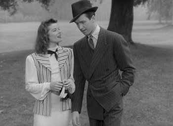 Movie still from “The Philadelphia Story” (1940), directed by George Cukor – A man and a woman standing next to each other in front of a tree; Medium shot, High angle