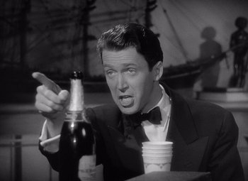 Movie still from “The Philadelphia Story” (1940), directed by George Cukor – A black and white photo of a man holding a bottle of wine; Close Up shot, Low angle