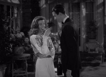 Movie still from “The Philadelphia Story” (1940), directed by George Cukor – A man and a woman standing next to each other holding wine glasses; Medium shot, High angle