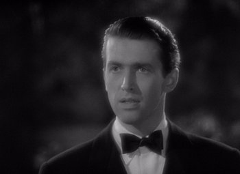 Movie still from “The Philadelphia Story” (1940), directed by George Cukor – A black and white photo of a man wearing a suit and bow tie; Close Up shot, High angle