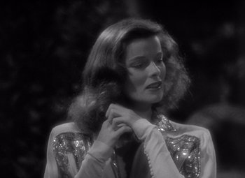 Movie still from “The Philadelphia Story” (1940), directed by George Cukor – A black - and - white photo of a woman adjusting her hair; Close Up shot, Over the shoulder angle