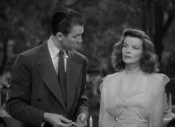 Movie still from “The Philadelphia Story” (1940), directed by George Cukor – A man and a woman standing next to each other in front of trees; Medium shot, High angle