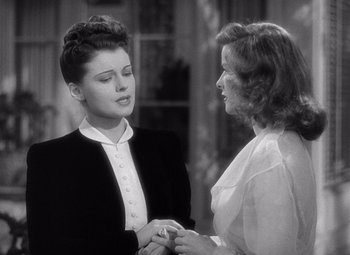 Movie still from “The Philadelphia Story” (1940), directed by George Cukor – Two women are holding each others hands in an old photo; Medium shot, Over the shoulder angle