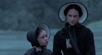 Movie still from “The Piano” (1993), directed by Jane Campion – Two women in black clothes and hats standing next to each other; Close Up shot, Over the shoulder angle