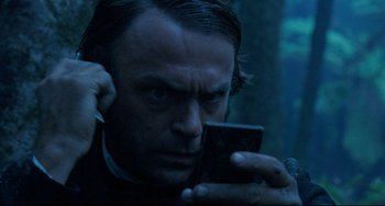 Movie still from “The Piano” (1993), directed by Jane Campion – A man holding a cell phone up to his ear; Close Up shot, Low angle