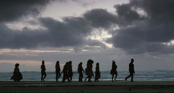 Movie still from “The Piano” (1993), directed by Jane Campion – A group of people walking along the beach; Wide shot, Low angle