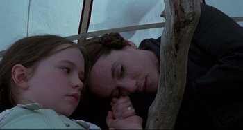 Movie still from “The Piano” (1993), directed by Jane Campion – A man and a girl laying next to each other; Close Up shot, High angle