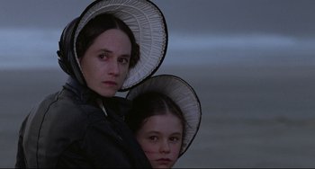 Movie still from “The Piano” (1993), directed by Jane Campion – A woman and a girl wearing hats are standing next to each other; Close Up shot, High angle