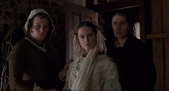 Movie still from “The Piano” (1993), directed by Jane Campion – A woman with two other women standing next to a door; Medium shot, Over the shoulder angle