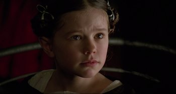 Movie still from “The Piano” (1993), directed by Jane Campion – A little girl wearing a white dress and a flower in her hair; Close Up shot, High angle