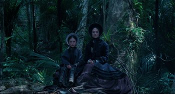 Movie still from “The Piano” (1993), directed by Jane Campion – Two women sitting in the woods wearing period clothing; Wide shot, Low angle