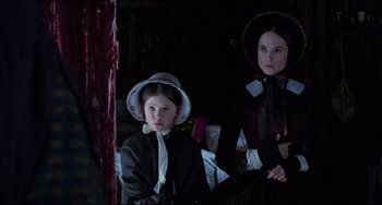 Movie still from “The Piano” (1993), directed by Jane Campion – Two women dressed in period clothing sitting next to each other; Medium shot, Over the shoulder angle