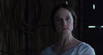 Movie still from “The Piano” (1993), directed by Jane Campion – A woman in a white shirt is looking at the camera; Close Up shot, Low angle