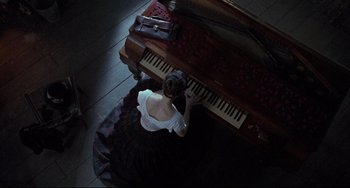 Movie still from “The Piano” (1993), directed by Jane Campion – A woman in a white dress is playing a piano; Wide shot, Overhead angle