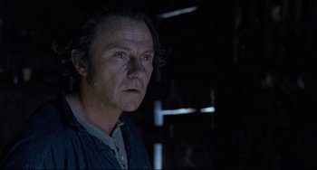 Movie still from “The Piano” (1993), directed by Jane Campion – A man in a dark room looking to his left; Close Up shot, Low angle