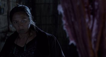 Movie still from “The Piano” (1993), directed by Jane Campion – A man in a black shirt is standing in the dark; Close Up shot, Over the shoulder angle