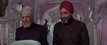 Movie still from “The Pink Panther” (1963), directed by Blake Edwards – Two men wearing turbans in a room with pink walls; Medium shot, High angle