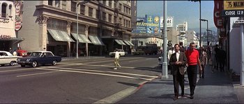 Movie still from “The Pink Panther” (1963), directed by Blake Edwards – A person riding a skate board on a city street; Extreme Wide shot, Over the shoulder angle