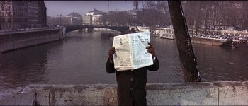 Movie still from “The Pink Panther” (1963), directed by Blake Edwards – A man reading a newspaper near a body of water; Medium shot, High angle