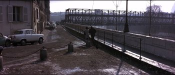 Movie still from “The Pink Panther” (1963), directed by Blake Edwards – Two people standing on the side of a road near a bridge; Extreme Wide shot, High angle