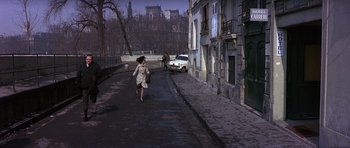 Movie still from “The Pink Panther” (1963), directed by Blake Edwards – A woman walking down a street with a car parked in the background; Wide shot, High angle