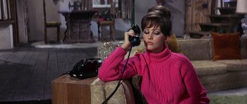 Movie still from “The Pink Panther” (1963), directed by Blake Edwards – A woman in a pink sweater is talking on a phone; Medium shot, High angle