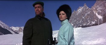 Movie still from “The Pink Panther” (1963), directed by Blake Edwards – A man and a woman standing next to each other in front of a snowy mountain; Medium shot, Low angle