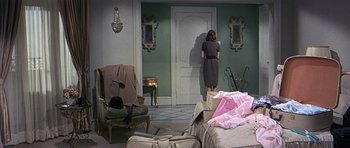 Movie still from “The Pink Panther” (1963), directed by Blake Edwards – A woman standing in front of an open door in a living room; Wide shot, High angle