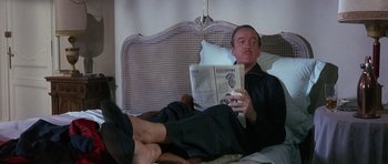 Movie still from “The Pink Panther” (1963), directed by Blake Edwards – A man is reading a newspaper while laying in a bed; Medium shot, Low angle