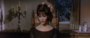 Movie still from “The Pink Panther” (1963), directed by Blake Edwards – A woman sitting in a wooden chair wearing a black dress; Close Up shot, Over the shoulder angle