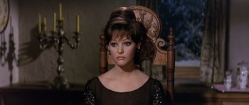 Movie still from “The Pink Panther” (1963), directed by Blake Edwards – A woman sitting in a wooden chair wearing a black dress; Close Up shot, Over the shoulder angle