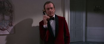 Movie still from “The Pink Panther” (1963), directed by Blake Edwards – A man in a red jacket holding a phone up to his ear; Medium shot, Low angle