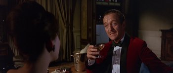 Movie still from “The Pink Panther” (1963), directed by Blake Edwards – A man sitting at a table holding a wine glass; Close Up shot, Over the shoulder angle