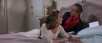 Movie still from “The Pink Panther” (1963), directed by Blake Edwards – A woman sitting on top of a bed next to a man; Medium shot, Over the shoulder angle