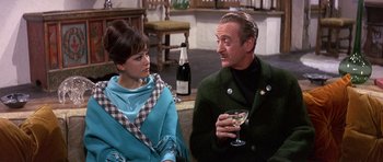 Movie still from “The Pink Panther” (1963), directed by Blake Edwards – An older man and a young woman sitting next to each other holding wine glasses; Medium shot, Over the shoulder angle