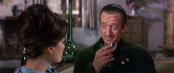 Movie still from “The Pink Panther” (1963), directed by Blake Edwards – An older man holding a wine glass in front of a young woman; Close Up shot, Over the shoulder angle